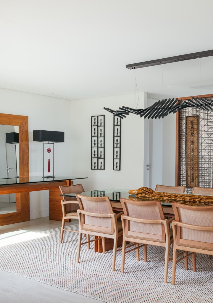 Cobertura tem sauna com paredes de vidro e área gourmet com balanços. Projeto de Vivian Reimers. Na foto, sala de jantar, mesa com tampo de vidro.