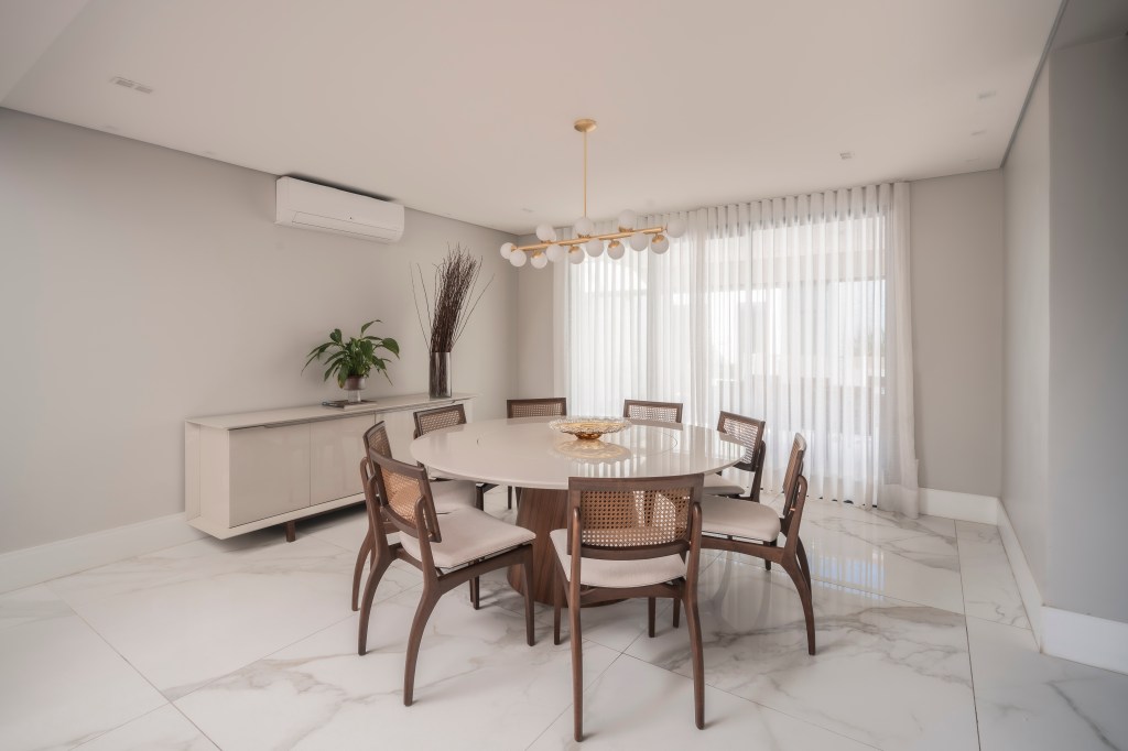 Com 500 m², casa clean tem paleta clara, closet e cozinha provençal. Projeto de PB Arquitetura. Na foto, sala de jantar com mesa redonda, paleta branca, piso marmorizado.