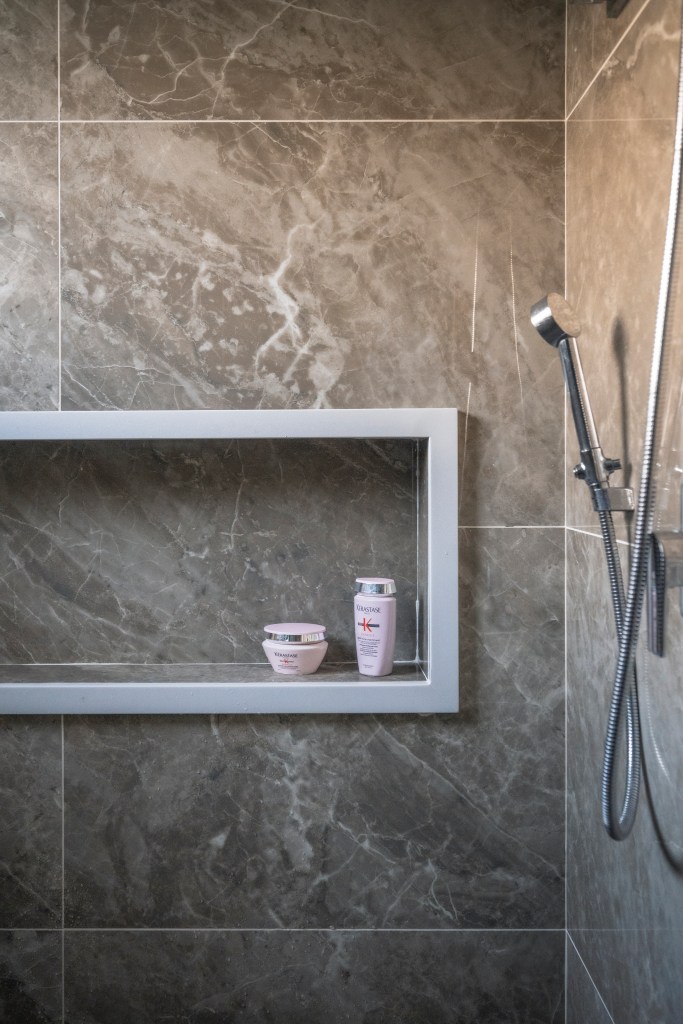 Com 500 m², casa clean tem paleta clara, closet e cozinha provençal. Projeto de PB Arquitetura. Na foto, banheiro com revestimento marmorizado, nicho no box.