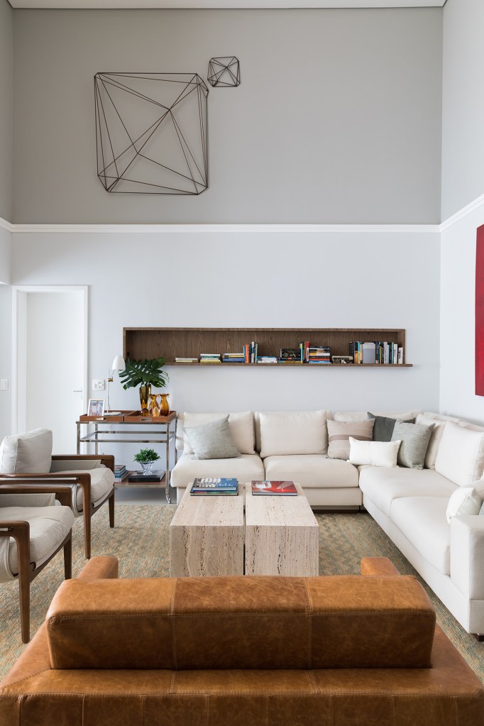 Cores diferentes criam efeitos de altura em apê com pé-direito duplo. Projeto de Caio Nazar. Na foto, prateleira sobre o sofá na sala.
