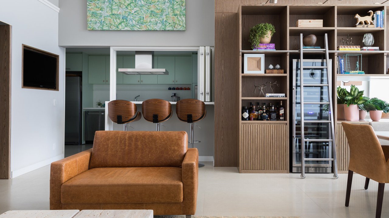 Cores diferentes criam efeitos de altura em apê com pé-direito duplo. Projeto de Caio Nazar. Na foto, sala com estante, jantar e cozinha integrada.