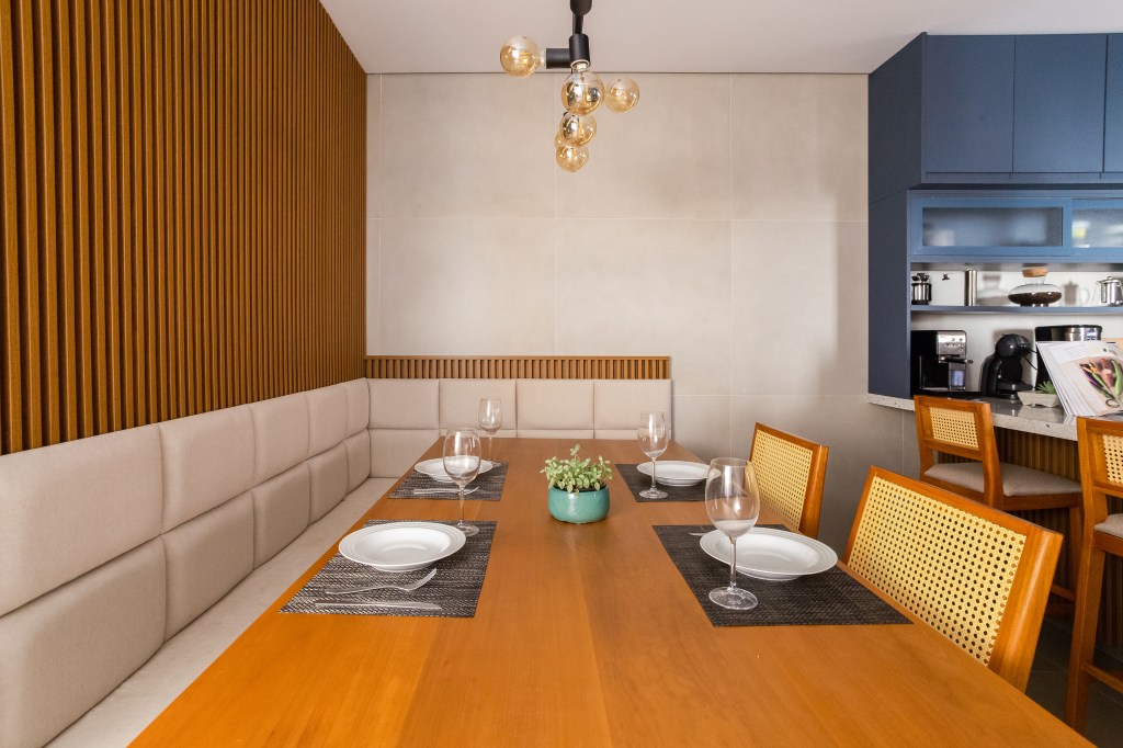 Cozinha com marcenaria azul e toque retrô tem canto alemão e canto do café. Projeto de Camilla Bischoff. Na foto, canto alemão, parede ripada, mesa de madeira.