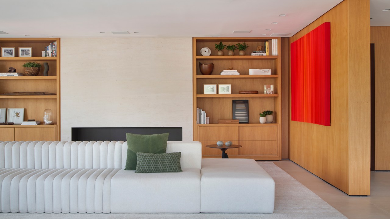 Décor minimalista, luz natural e ambientes integrados marcam apê de 350 m². Projeto de Arkitekt Associados. Na foto, sala com parede de madeira e quadros.