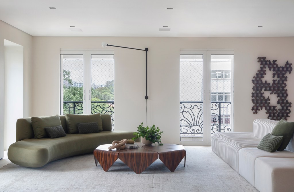 Décor minimalista, luz natural e ambientes integrados marcam apê de 350 m². Projeto de Arkitekt Associados. Na foto, sala com sofá curvo verde, varanda e luminária.
