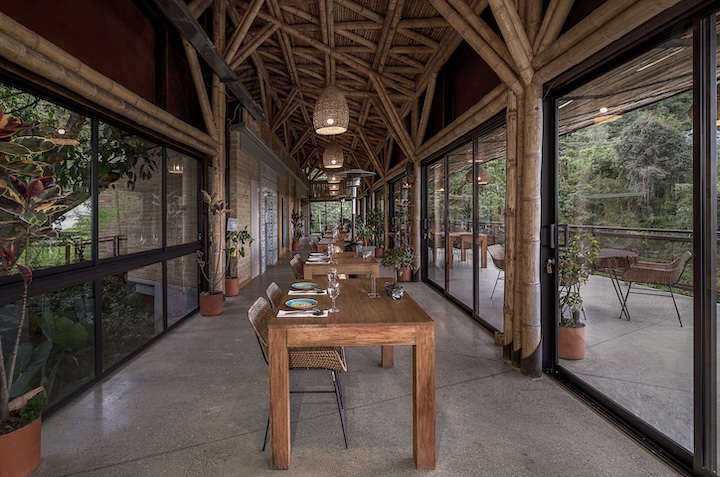 Hotel sustentável na Colômbia tem área de reflorestamento e permacultura. Na foto, interior de cabana com mesa grande de madeira.