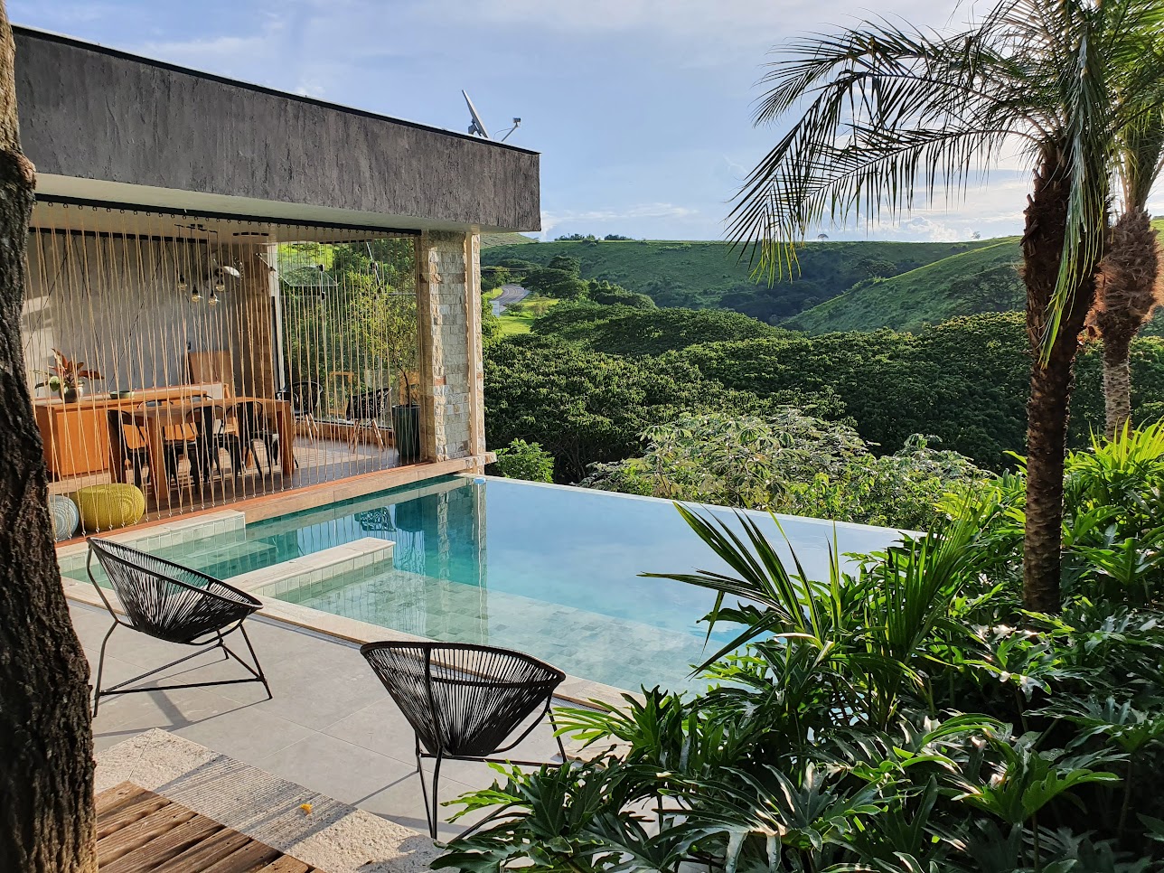 Jardim de 200 m² tem paisagismo tropical e lago que funciona como piscina. Projeto de Júlio Sousa, Na foto, piscina com borda infinita e varanda.