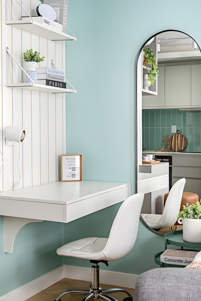 Microapê de 26 m² tem cozinha completa, home office e cantinho de café. Projeto de Go Up Arquitetura. Na foto, home office pequeno com mesa e cadeira branca, espelho, prateleira pequena.