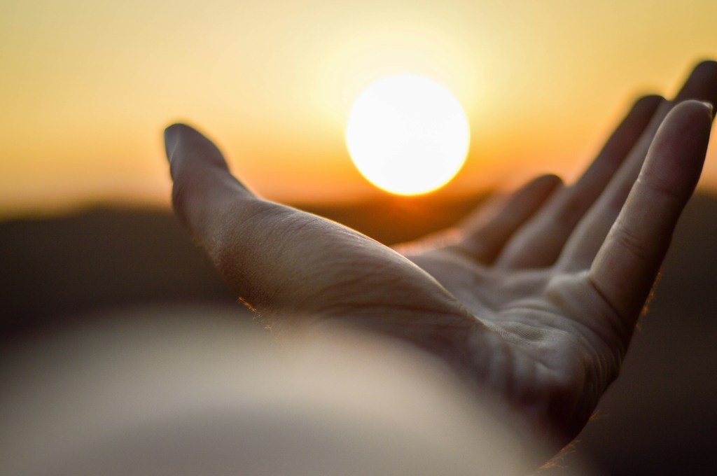 O que fazer na quaresma: simpatias e orações para prosperidade e proteção. Na foto, mão estendida em direção ao sol.