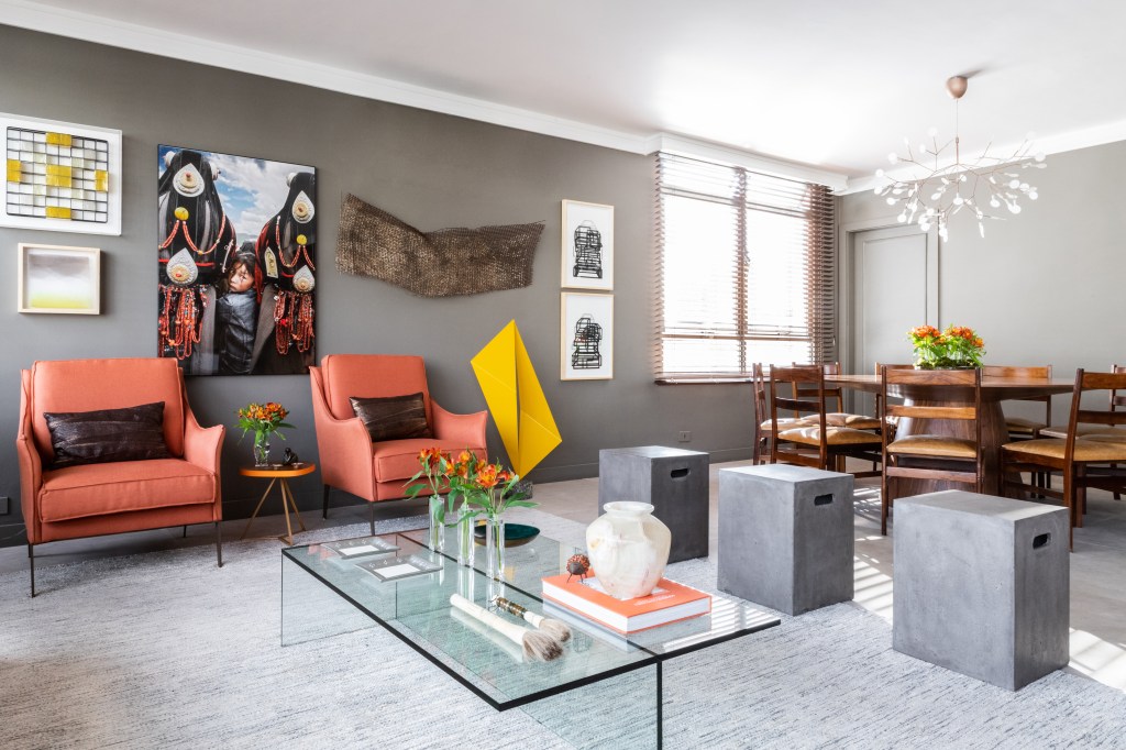 Peças garimpadas marcam o décor sofisticado deste apartamento de 370 m². Projeto de Renata Patelli. Na foto, sala de estar com sofá cinza e obra de arte.