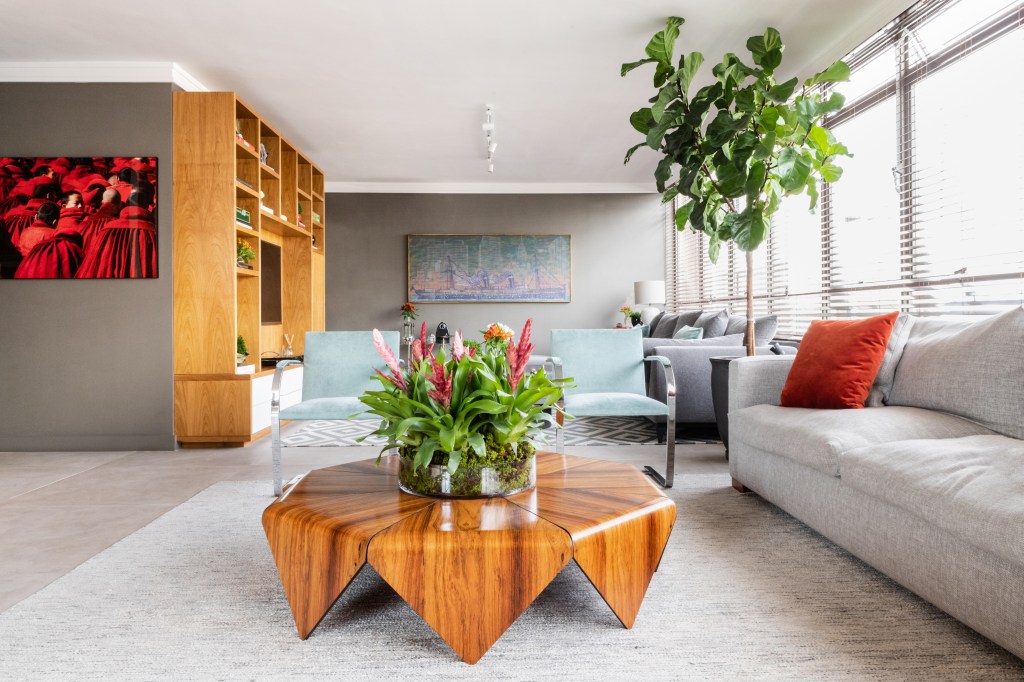 Peças garimpadas marcam o décor sofisticado deste apartamento de 370 m². Projeto de Renata Patelli. Na foto, sala de estar com quadros, sofás e plantas.