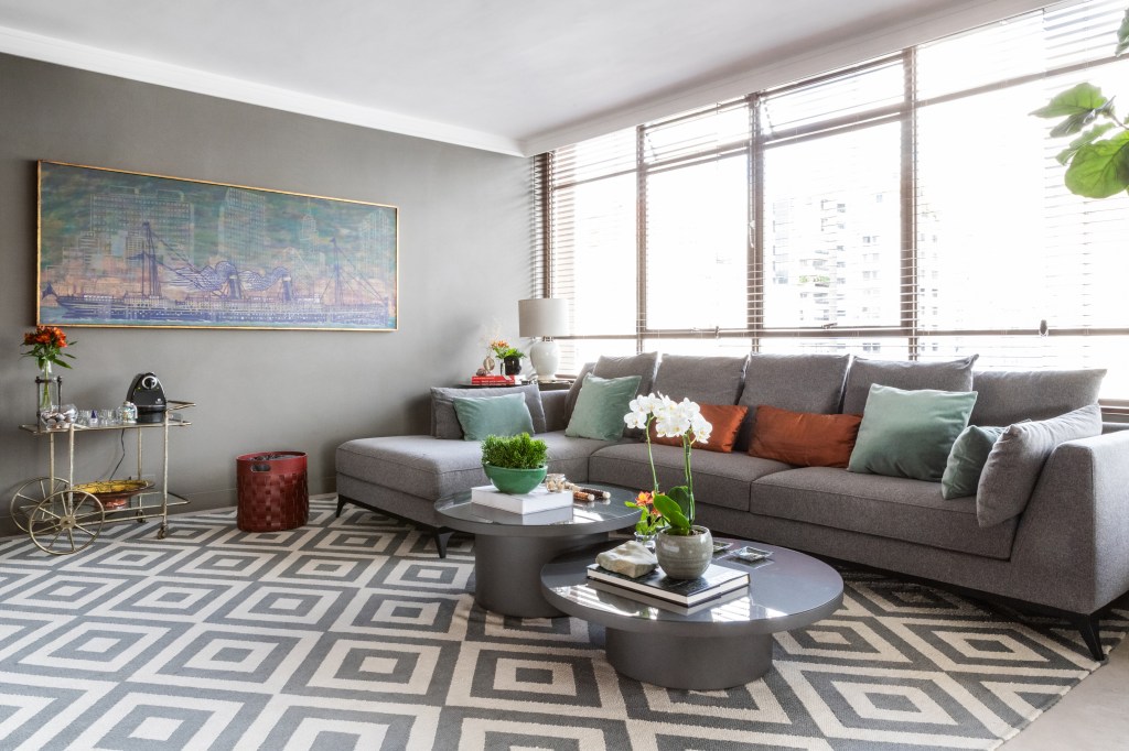 Peças garimpadas marcam o décor sofisticado deste apartamento de 370 m². Projeto de Renata Patelli. Na foto, sala de estar com sofá, tapete e plantas.