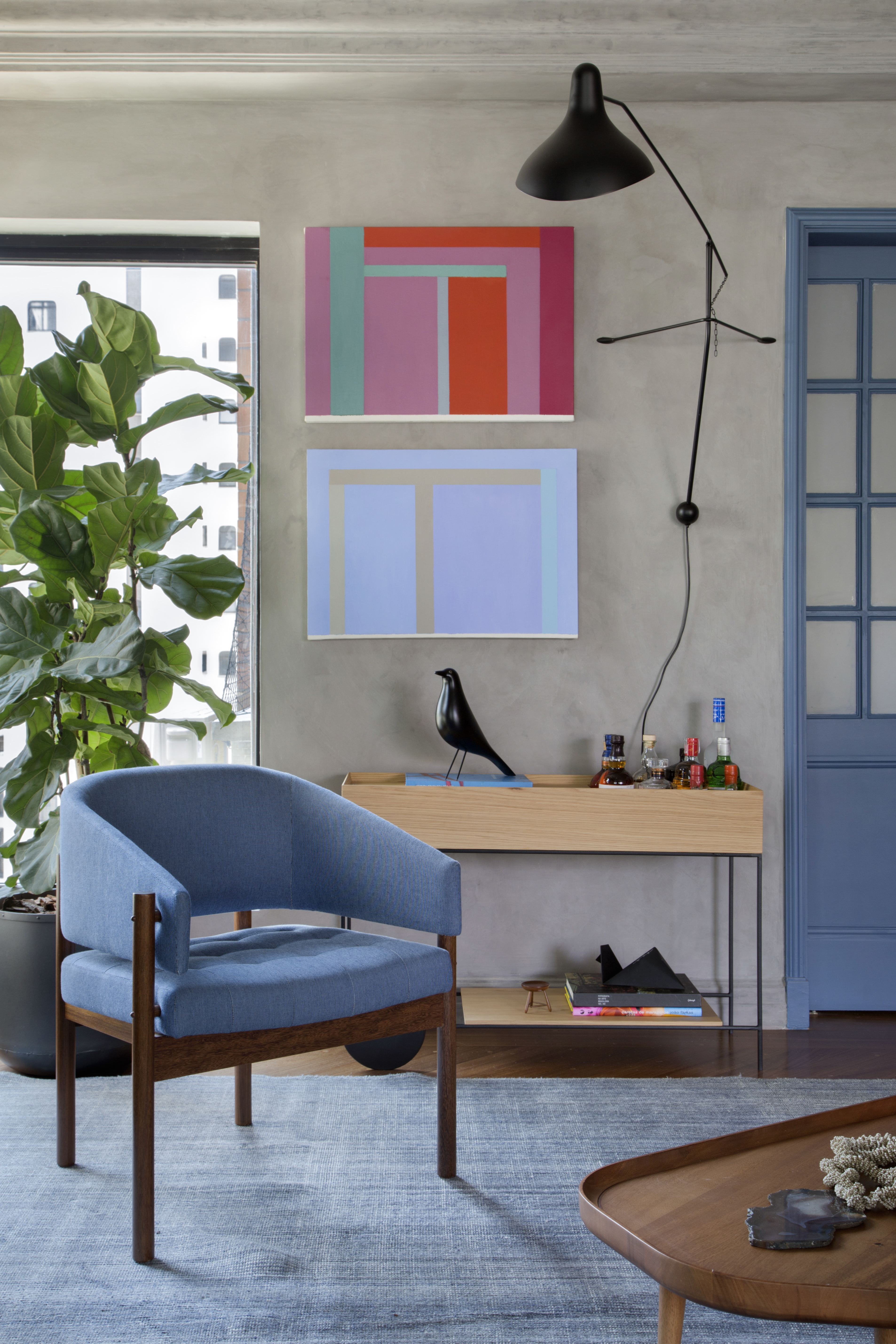 Quadros e cores dão personalidade e charme à apê reformado em 60 dias. Projeto de Ar.Kitekt Associados. Na foto, sala de estar, planta ficus, poltrona azul, carrinho de chá, parede de cimento, quadros.