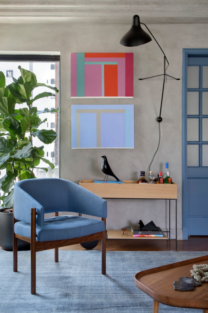 Quadros e cores dão personalidade e charme à apê reformado em 60 dias. Projeto de Ar.Kitekt Associados. Na foto, sala de estar, planta ficus, poltrona azul, carrinho de chá, parede de cimento, quadros.