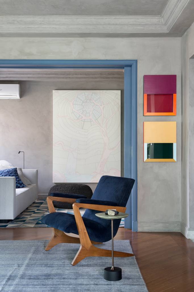 Quadros e cores dão personalidade e charme à apê reformado em 60 dias. Projeto de Ar.Kitekt Associados. Na foto, sala de estar com poltrona azul, parede e teto revestido de cimento queimado.