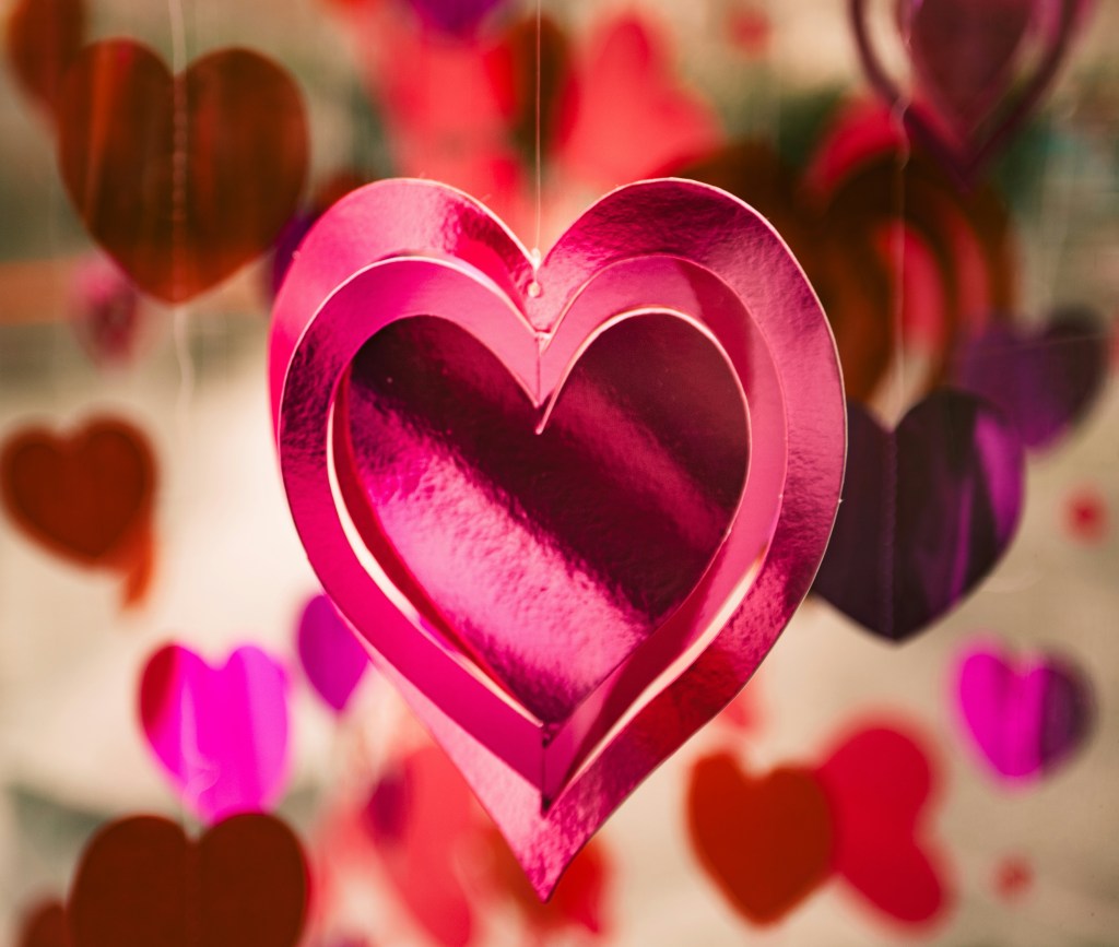 5 simpatias para atrair um amor no Carnaval. Na foto, enfeite de coração de papel rosa pendurado.