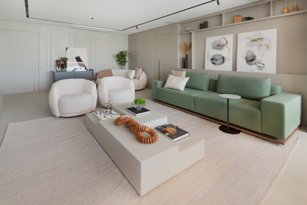 Sofá verde inspira a paleta de cores deste apartamento com décor clássico. Projeto de ADVP. Na foto, sala com sofá curvo e aparador. Sofá verde e tv,