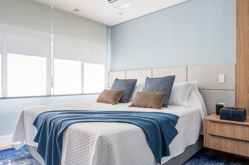 Tons de azul e integração total na área social marcam apê de 107 m². Projeto de Daniela Funari. Na foto, quarto de casal com parede azul, persiana, manta azul.