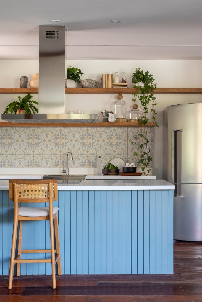 Tons naturais e base neutra marcam casa de campo com cozinha provençal. Projeto de João Panaggio. Na foto, cozinha em estilo provençal, azulejos, ilha com bancada branca e revestimento azul ripado.