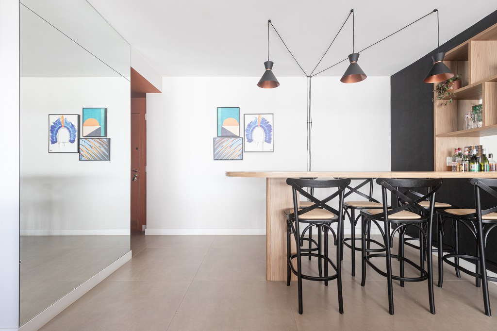 Uma única bancada une área gourmet e cozinha neste apê de 90 m². Projeto de Livia Dalmaso. Na foto, sala de jantar com mesa orgânica e bar.