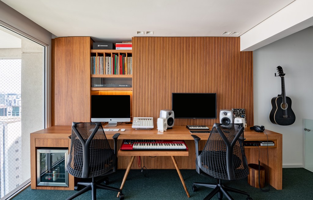 Apartamento de 170 m² com pé-direito duplo tem estúdio de DJ no mezanino. Projeto de Carolina Esper. Na foto, estúdio de música com carpete e marcenaria ripada.