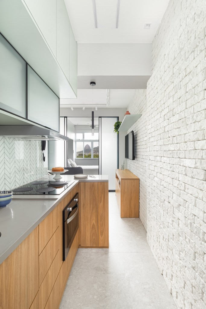 Apê de apenas 20 m² tem vista para o Pão de Açúcar e parede de tijolinhos. Projeto de MA.DÊ Arquitetura. Na foto, cozinha com parede de tijolinho.