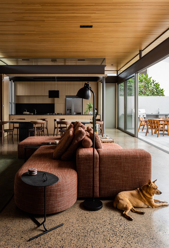 Casa de 168 m² em terreno triangular possui duas partes com usos distintos. Projeto de Studio Porto. Na foto, living com sofá ilha e cozinha integrada.