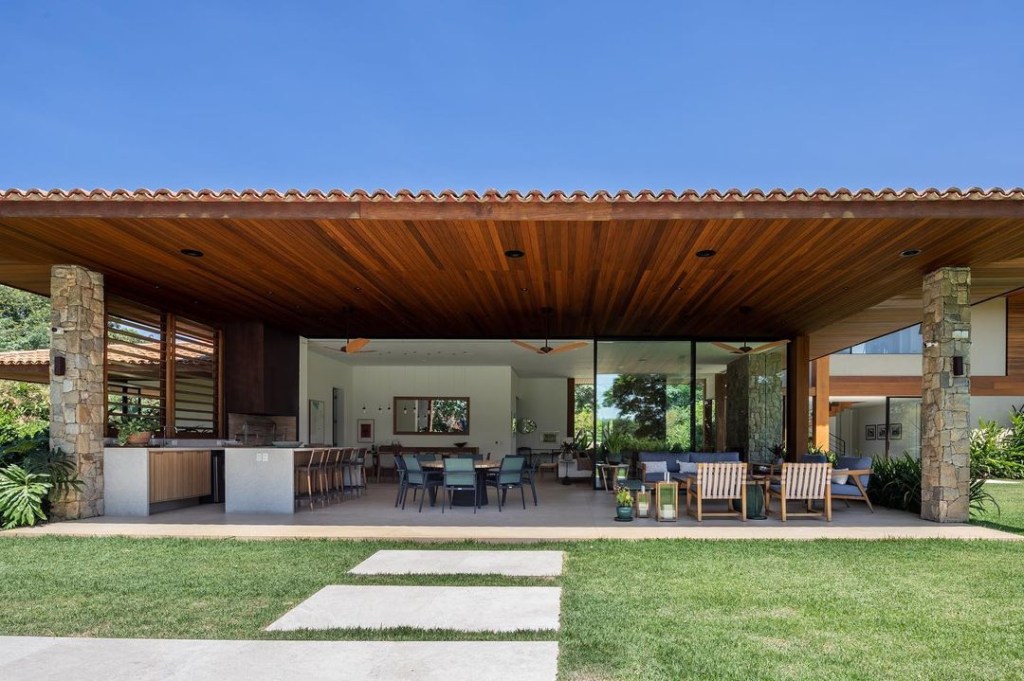 Casa de campo de 600 m² é projetada a partir da natureza do entorno. Projeto Gilda Meirelles Arquitetura. Na foto, varanda integrada com o jardim com espaço gourmet.