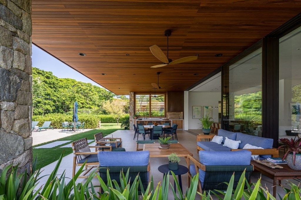 Casa de campo de 600 m² é projetada a partir da natureza do entorno. Projeto Gilda Meirelles Arquitetura. Na foto, sala de estar e varanda com vista para o jardim.