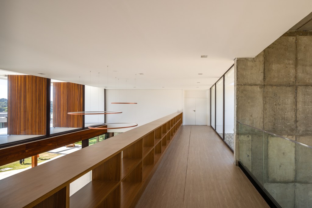 Casa é composta por três volumes ligados por pergolado de madeira. Projeto de Arkitito. Na foto, corredor.