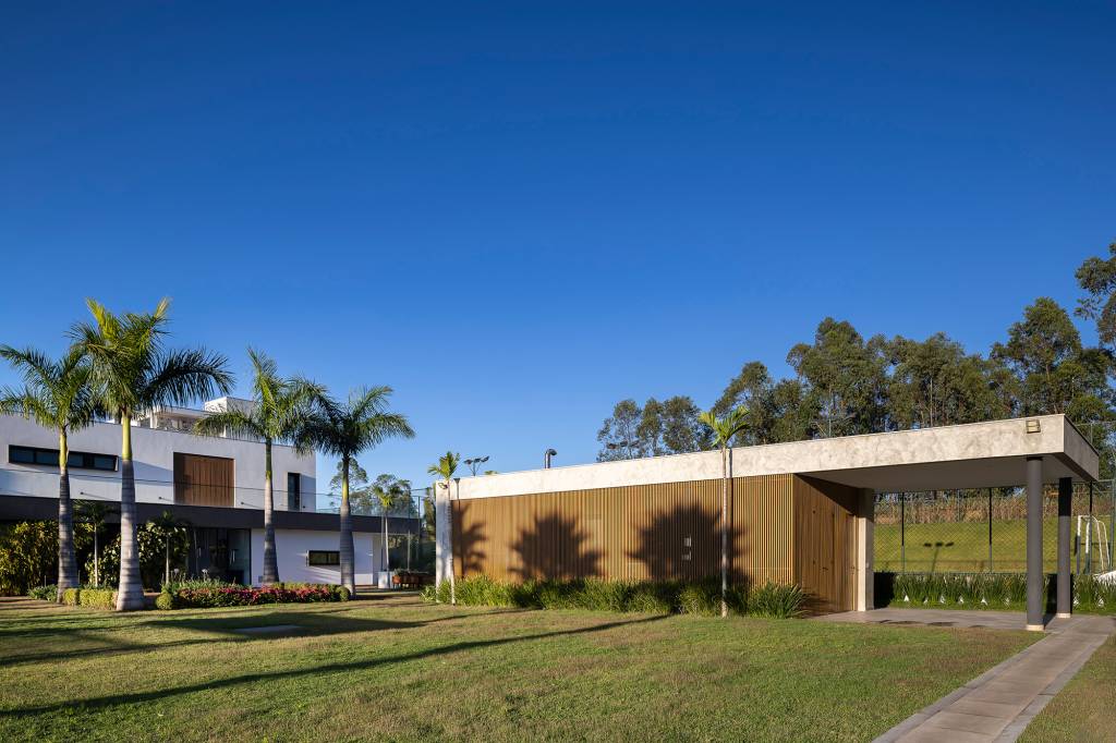 Casa de campo tira partido do aclive do terreno para criar privacidade. Projeto de Raiz Arquitetura. Na foto, fachada da casa com jardim.