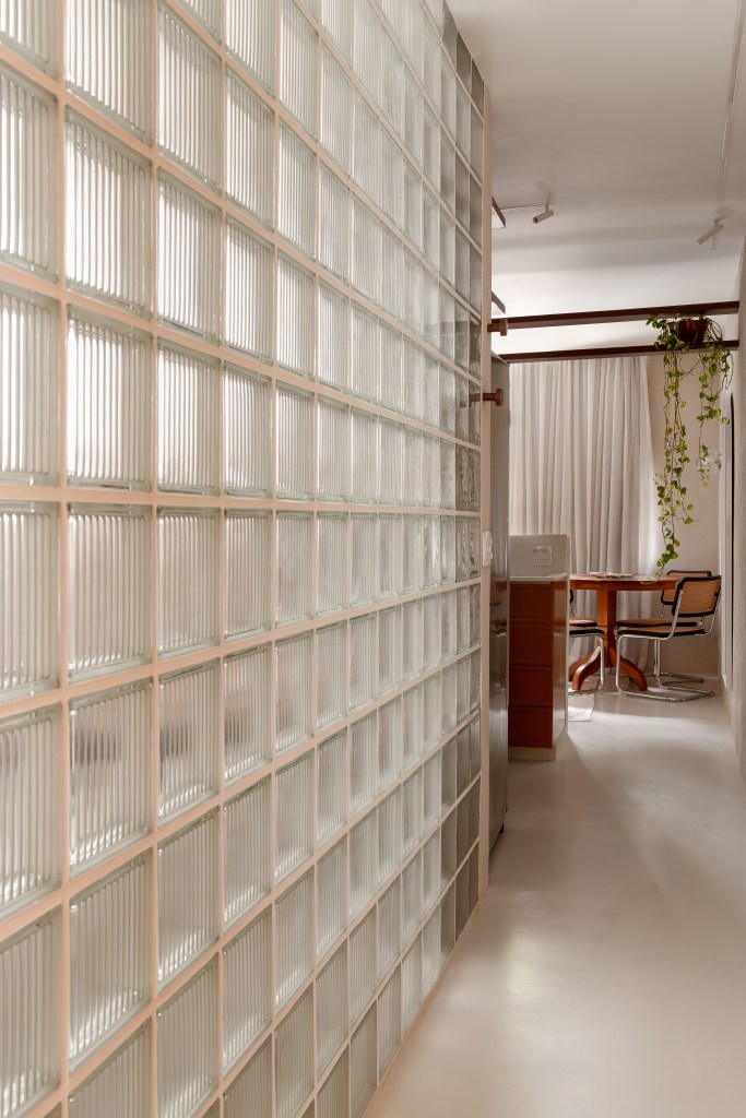 Com 33 m², studio com toque vintage usa tijolos de vidro como divisória. Projeto de Mariana Monnerat. Na foto, corredor com parede de tijolos.