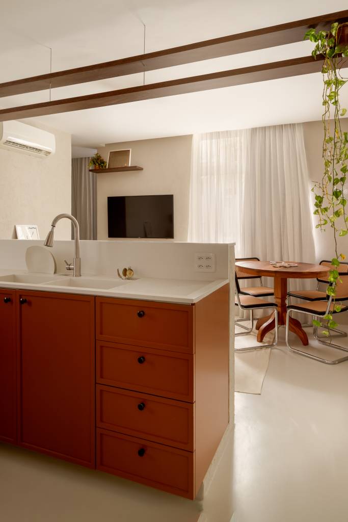 Com 33 m², studio com toque vintage usa tijolos de vidro como divisória. Projeto de Mariana Monnerat. Na foto, bancada de cozinha integrada branca.