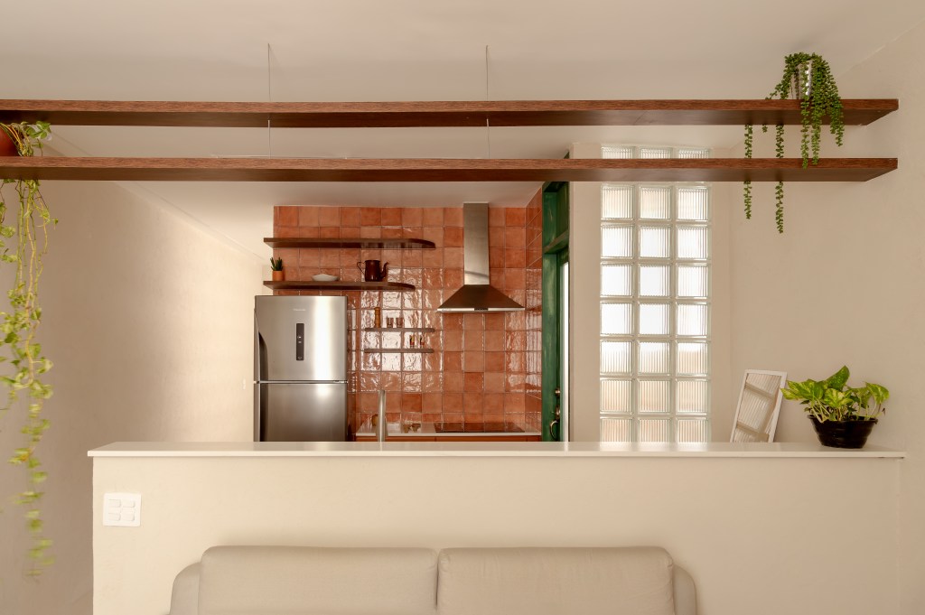 Com 33 m², studio com toque vintage usa tijolos de vidro como divisória. Projeto de Mariana Monnerat. Na foto, cozinha com azulejos terracota, porta verde.