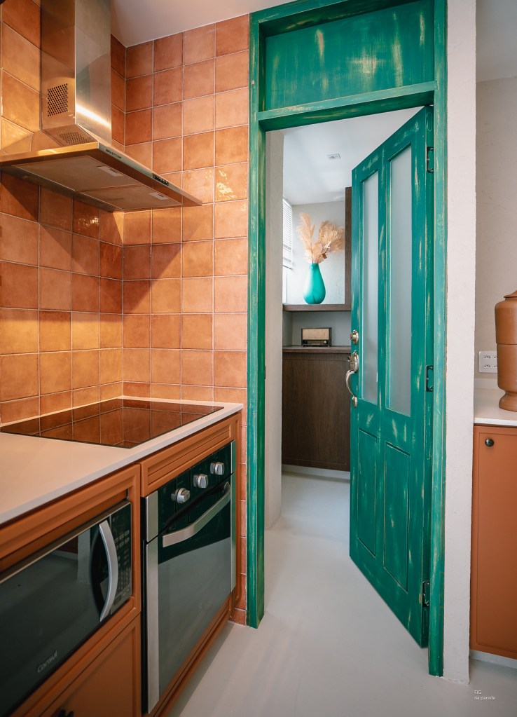 Com 33 m², studio com toque vintage usa tijolos de vidro como divisória. Projeto de Mariana Monnerat. Na foto, cozinha com azulejos terracota, porta verde.