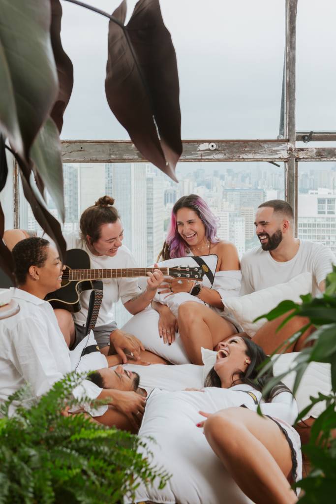 Como a escolha da cama influencia na decoração do quarto. Na foto, grupo de pessoas conversando e sorrindo em quarto.