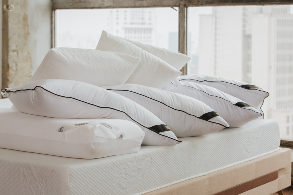 Como a escolha da cama influencia na decoração do quarto. Na foto, travesseiros brancos sobre cama.
