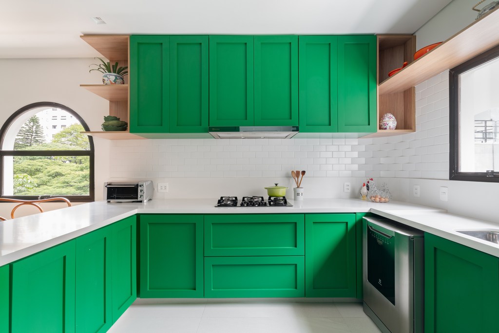 Cozinha verde, lavabo estampado e escorregador dão personalidade a apê. Projeto de Estúdio Pluri. Na foto, cozinha verde com copa e armários.