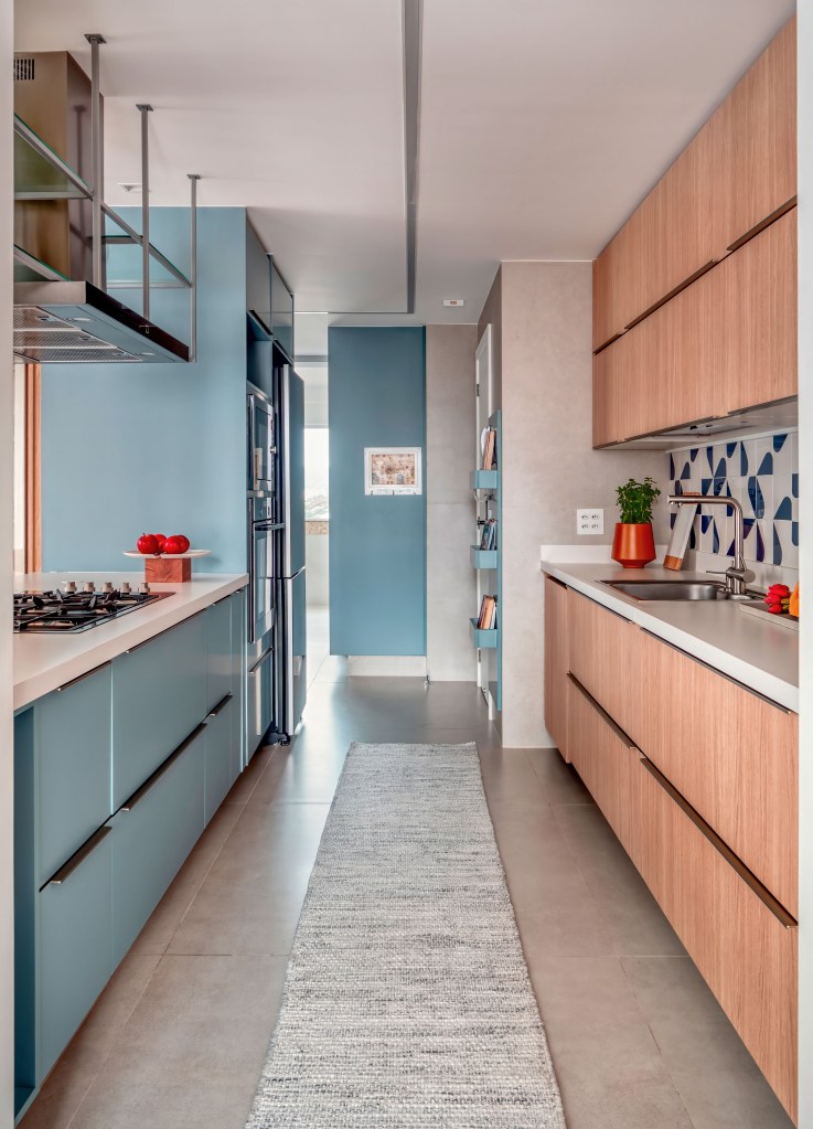 Cristaleira piso-teto rouba a cena na sala de jantar desta cobertura. Projeto de Paula Muller. Na foto, cozinha, parede azul com prateleiras, backsplash.
