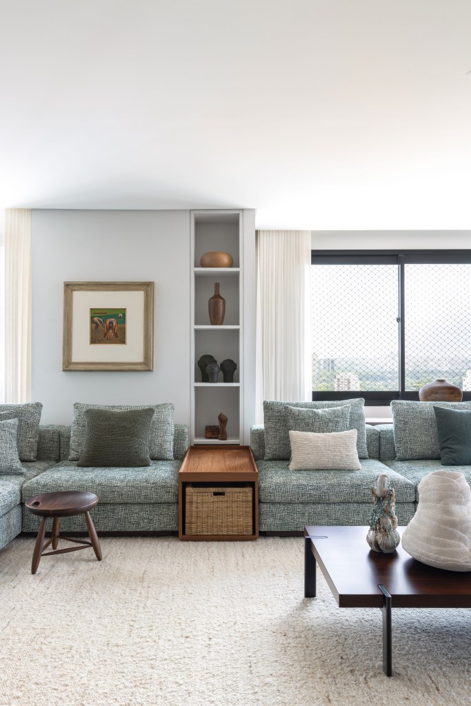Design e cozinha com piso de ladrilho verde são destaque em apê. Projeto de TODOS Arquitetura. Na foto, sala de estar, sofá grande modular, tapete bege.