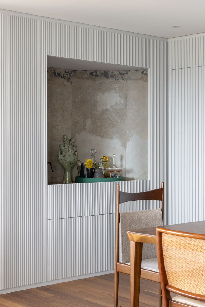 Design e cozinha com piso de ladrilho verde são destaque em apê. Projeto de TODOS Arquitetura. Na foto, painel ripado branco com nicho para bar.