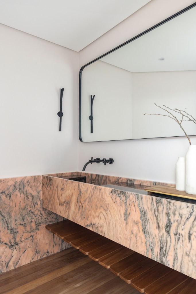 Design e cozinha com piso de ladrilho verde são destaque em apê. Projeto de TODOS Arquitetura. Na foto, lavabo com cuba esculpida em mármore, metais pretos.