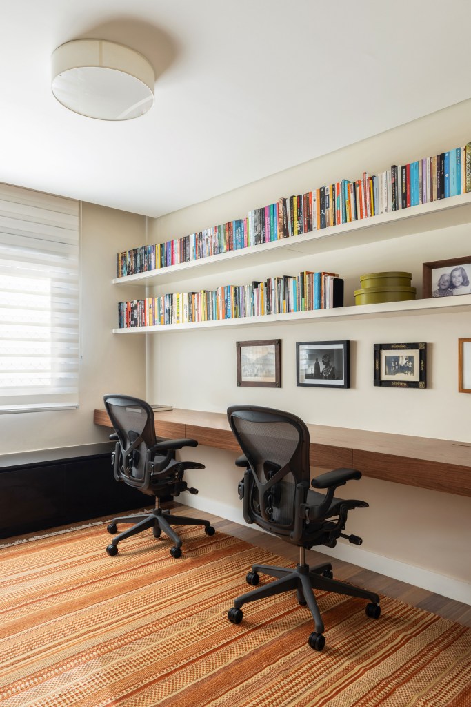 Design e cozinha com piso de ladrilho verde são destaque em apê. Projeto de TODOS Arquitetura. Na foto, home office duplo, bancada de madeira, prateleiras com livros.