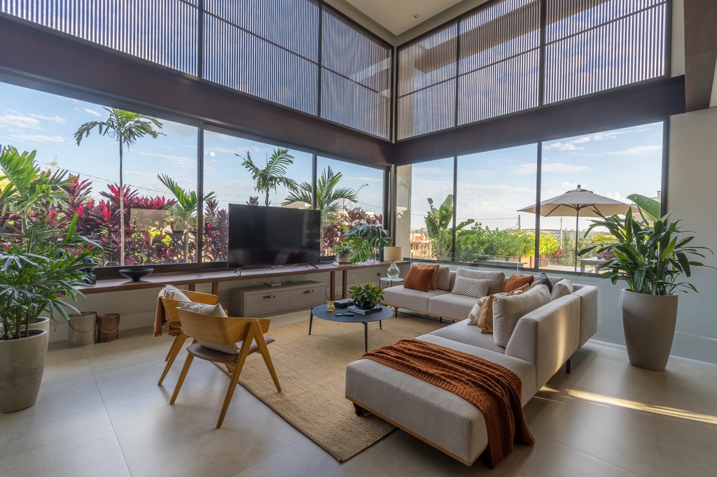 Grandes vãos de vidro integram esta casa de 600 m² à natureza do entorno. Projeto Beth Araújo. Na foto, sala de estar e jantar com vista para o jardim.