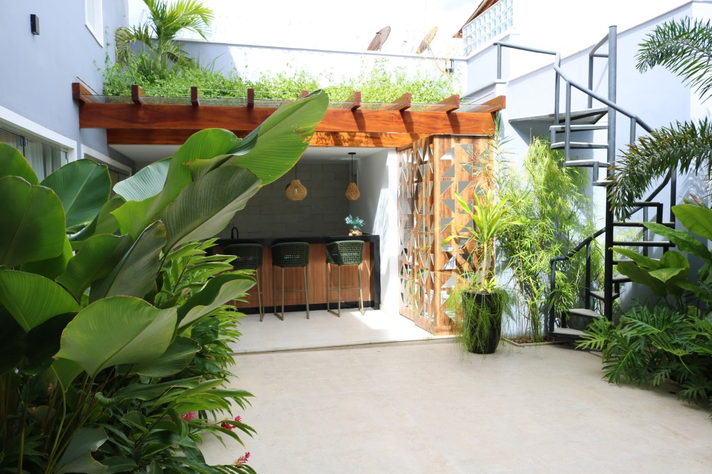 Jardim com canteiros e pergolado foi realizado em apenas 5 dias! Projeto de Stúdio Julio Sousa. Na foto, jardim com folhagens e parede lilás.