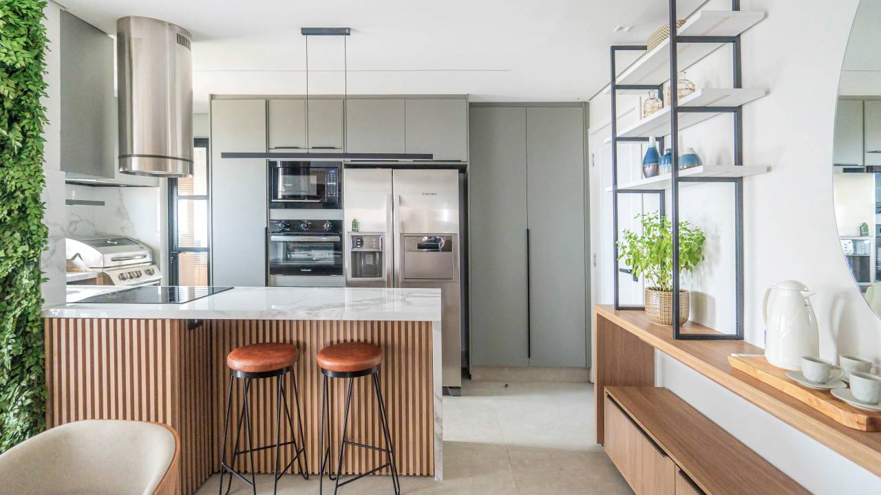 Layout e revestimentos de apê de 90 m² foram pensados para casal de idosos. Projeto de Larissa Albuquerque. Na foto, cozinha integrada, bancada marmorizada, banquetas.