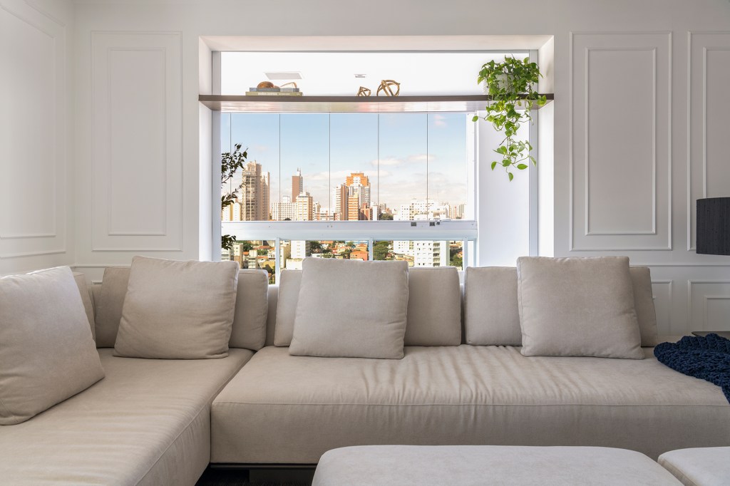 Madeira escura e vista para skyline trazem elegância para apê de 280 m². Projeto Studio Elã. Na foto, sala de estar com vista para a cidade e sofá.