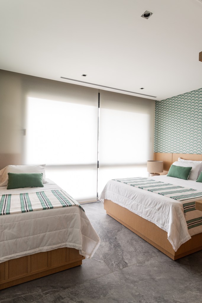 Mix de elementos artesanais, naturais e tecnologia definem casa de praia. Projeto de Patricia Penna. Na foto, quarto com uma cama de casal e uma cama de solteiro.