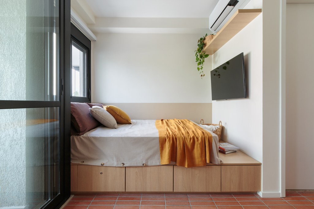 Piso de terracota e plantas criam frescor em apê de apenas 20 m². Projeto Estúdio Maré. Na foto, quarto com cama tablado e tv.