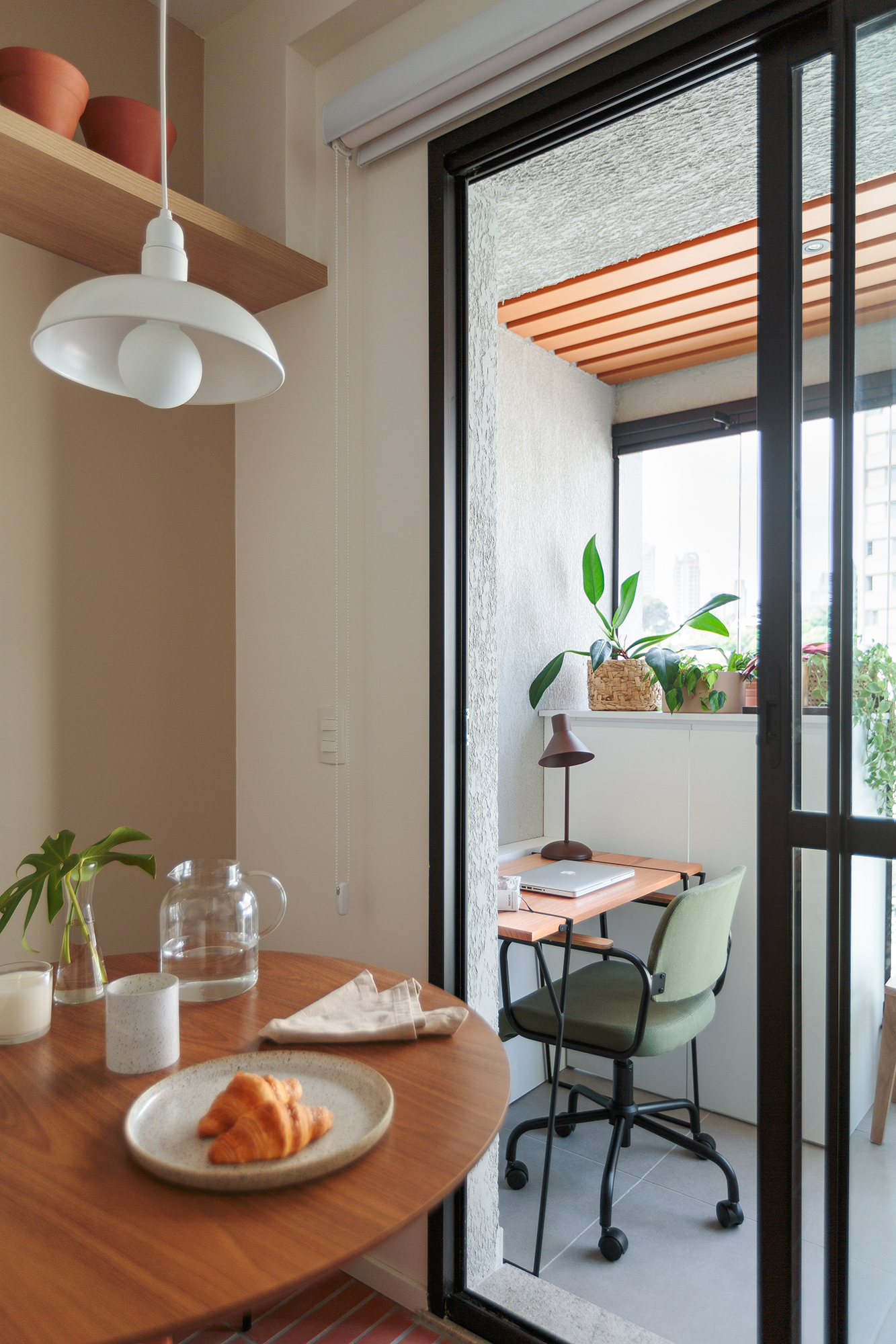 Piso de terracota e plantas criam frescor em apê de apenas 20 m². Projeto Estúdio Maré. Na foto, sala de jantar com mesa redonda e home office.