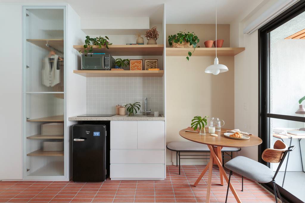 Piso de terracota e plantas criam frescor em apê de apenas 20 m². Projeto Estúdio Maré. Na foto, cozinha e jantar com marcenaria planejada e piso de terracota.